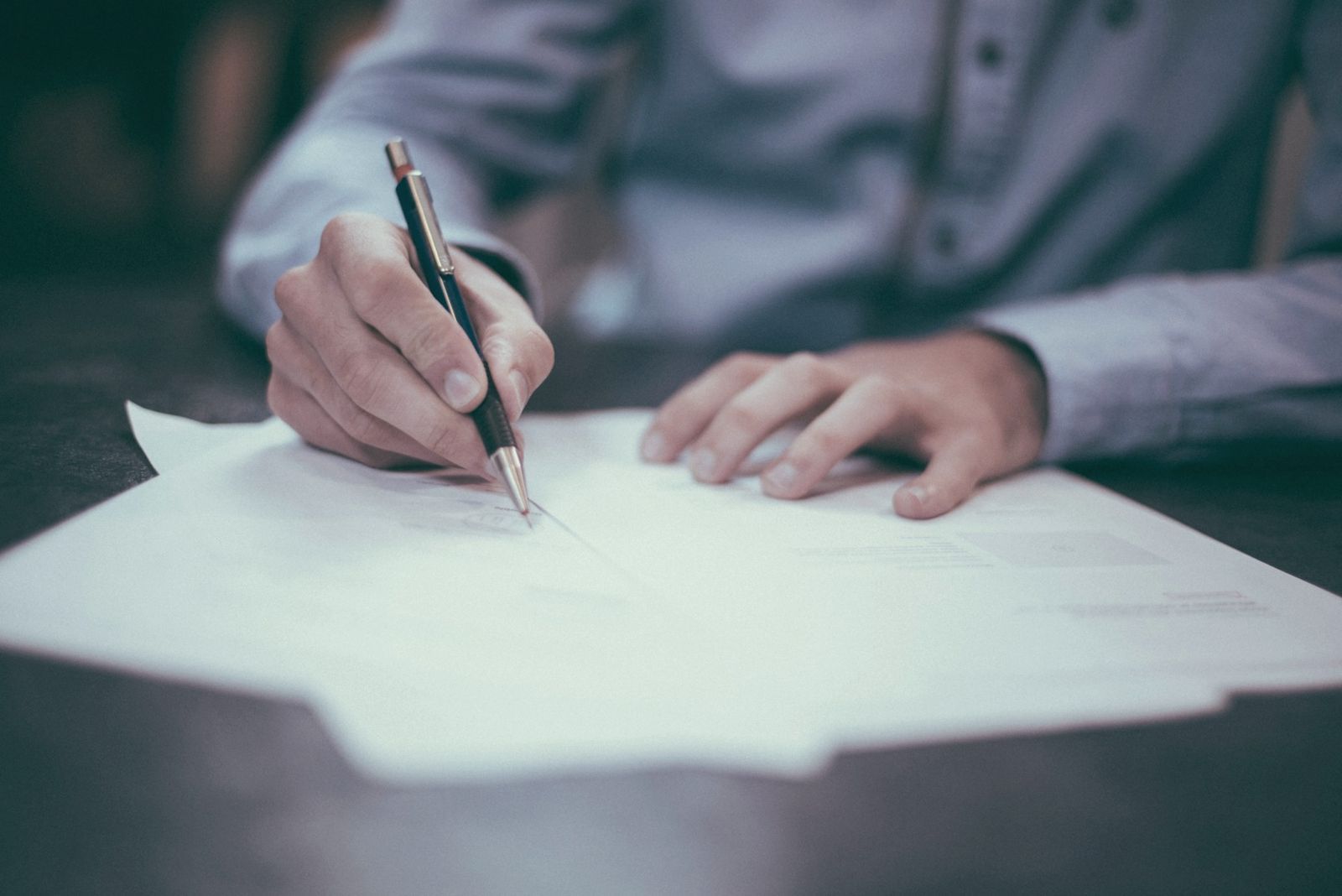 A hand reviewing and signing a written agreement